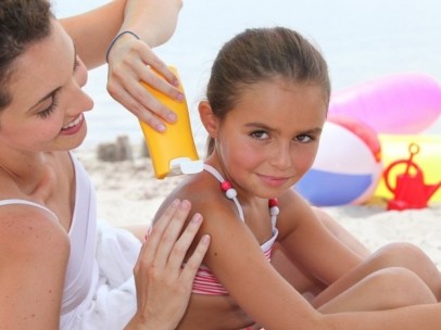 Una mujer aplica protector solar a una niña