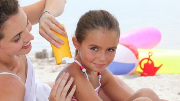 Una mujer aplica protector solar a una niña Una mujer aplica protector solar a una niña