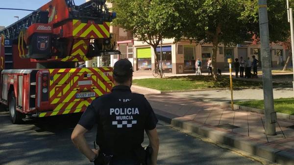 Un agente de la Policía de Murcia junto a un camión de bomberos. Un agente de la Policía de Murcia junto a un camión de bomberos.