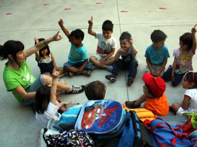 Niños junto a una monitora en el casal de verano de la escuela Fructuós Gelabert de Barcelona.