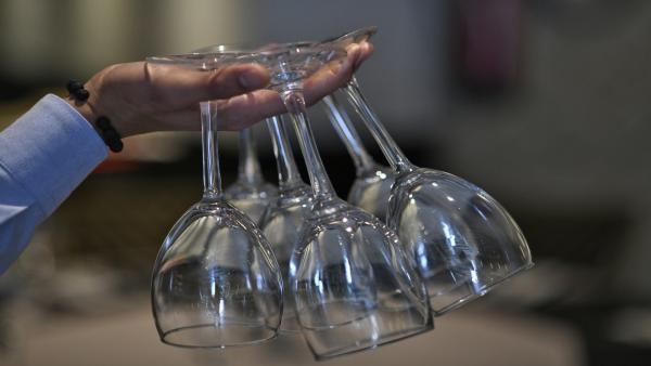 Un camarero sujeta copas de vino de cristal entre sus dedos. Un camarero sujeta copas de vino de cristal entre sus dedos.