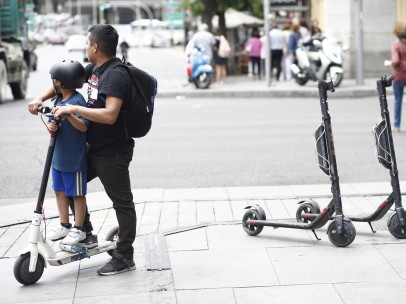 Un niño y un adulto montando en un patinete eléctrico en la calle Goya de Madrid.