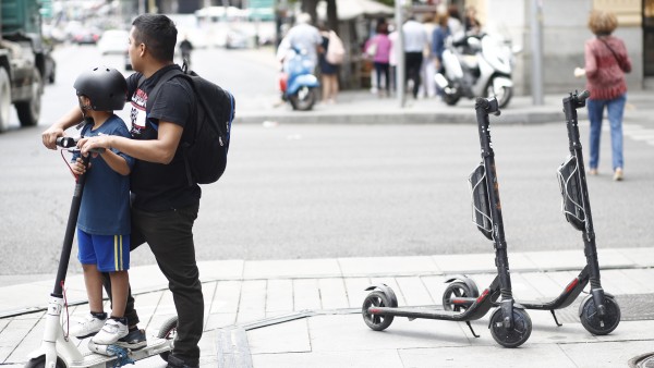 Un niño y un adulto montando en un patinete eléctrico en la calle Goya de Madrid. Un niño y un adulto montando en un patinete eléctrico en la calle Goya de Madrid.