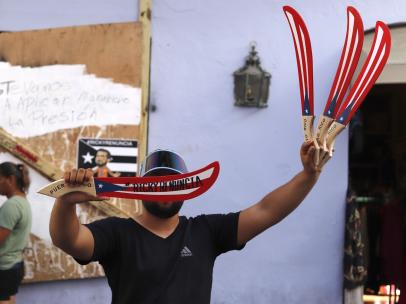 Un vendedor ambulante muestra este miércoles una artesanía con el mensaje "Ricky renuncia"