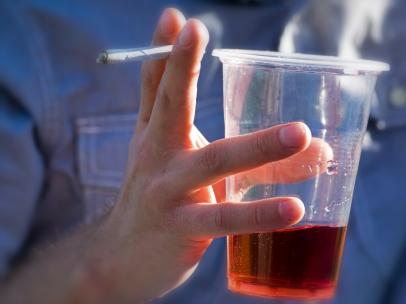 Un joven sujeta un cigarrillo y un vaso con alcohol.