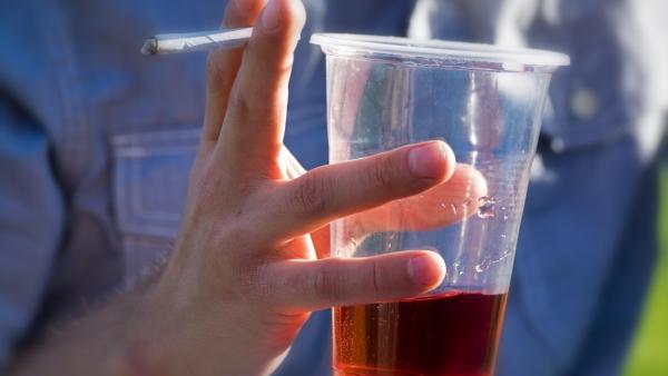 Un joven sujeta un cigarrillo y un vaso con alcohol. Un joven sujeta un cigarrillo y un vaso con alcohol.
