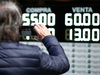 Un hombre toma una fotografía de los valores de compra y venta de la moneda argentina en Buenos Aires