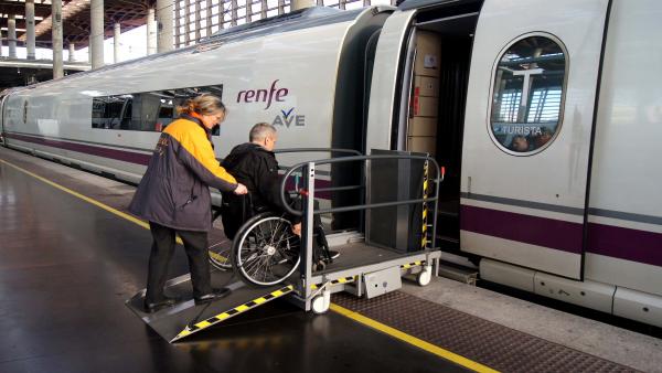 Servicio Atendo, personal ayuda a una persona con movilidad reducida a entrar en un tren AVE Servicio Atendo, personal ayuda a una persona con movilidad reducida a entrar en un tren AVE