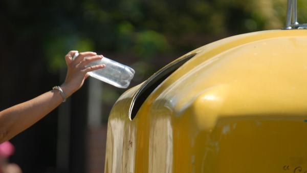Una persona arroja una botella de plástico al contenedor amarillo Una persona arroja una botella de plástico al contenedor amarillo
