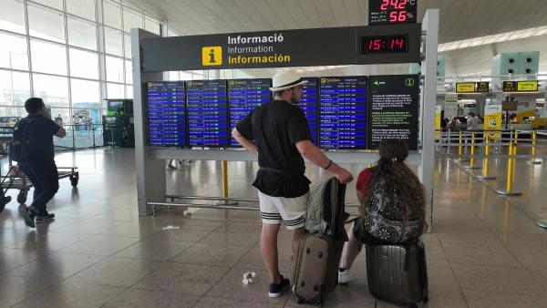 Pasajeros en el Aeropuerto de Barcelona ante un panel de información Pasajeros en el Aeropuerto de Barcelona ante un panel de información