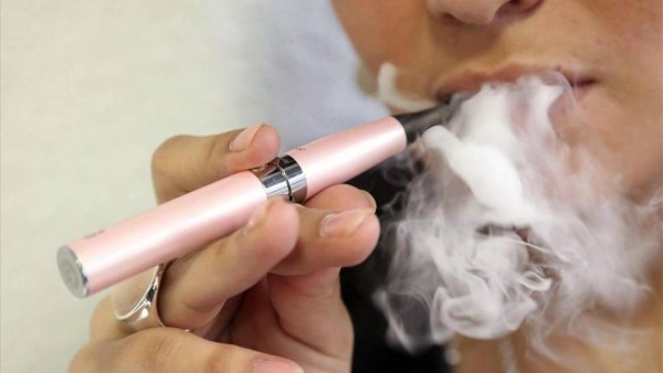 Mujer fumando un cigarrillo electrónico Mujer fumando un cigarrillo electrónico