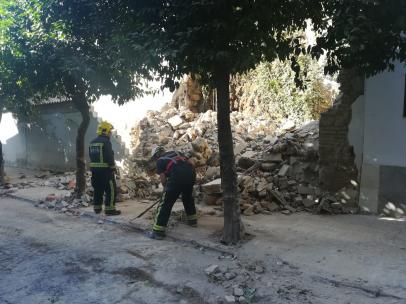 Dos bomberos junto al muro moderno y el trozo de muralla romana afectados por el derrumbe en la calle San Fernando de Córdoba.